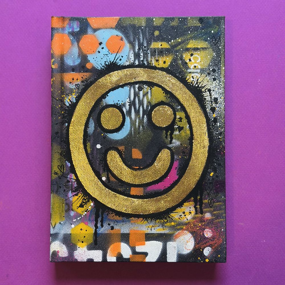 Shop item. Happy tears sketch book. Cover with spray paint and a gold leaf smiley face. £45